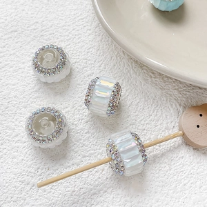 Détail de perles cylindriques blanches avec cristaux colorés pour création de bijoux