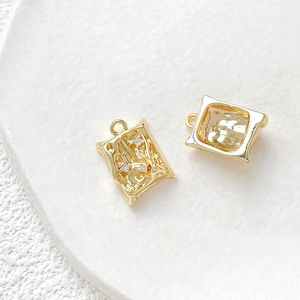 Macro detail of 18k gold plated textured dragon charms with cubic zirconia and smooth frame
