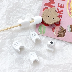 Close-up of white ghost-shaped cable protector with a smiley face on textured background