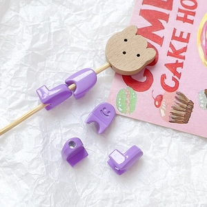 Macro view of purple resin boot-shaped beads with smiling face for DIY jewelry making