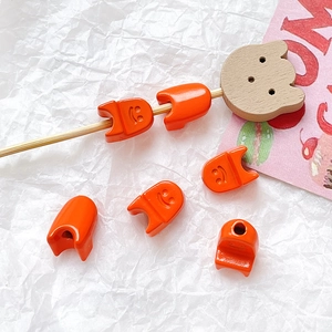 Macro detail of orange smiley face beads for DIY jewelry making on white background