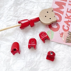 Macro view of red smiley face beads and wooden bear head pendants for DIY jewelry making