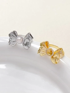 Detail of 18k gold and silver bow rings with sparkling zircons and elegant pearls