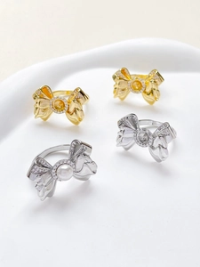 Macro detail of bow-shaped ring settings with 18k gold plating and cubic zirconia accents