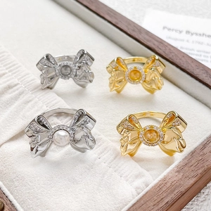 Bow-knot 18k gold plated ring with zircon accents and pearl settings on a tray
