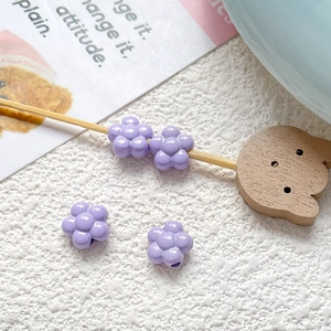 Macro detail of purple flower acrylic beads for DIY jewelry making on white textured background