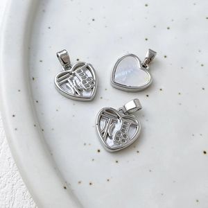 Macro view of heart-shaped silver pendant with white mother of pearl and FU character