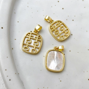Close-up of 14k gold plated double-sided XI character pendants with white mother of pearl