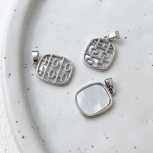 Macro detail of 14k gold-plated square pendant with natural white mother of pearl inlay
