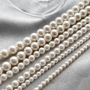 Lustrous white shell pearls in various sizes arranged on silk fabric for DIY jewelry making