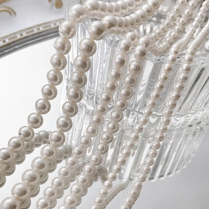 Detailed close-up of high-luster white shell pearl strands in various sizes for DIY jewelry