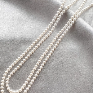 Macro shot of 4mm white shell pearls on grey satin for DIY jewelry making