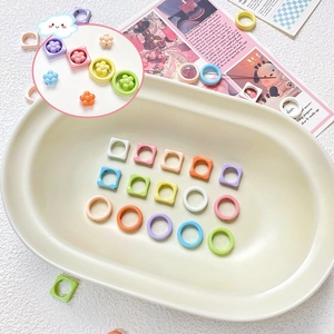 DIY jewelry making kit with macaron colored resin rings and flower beads in a ceramic dish