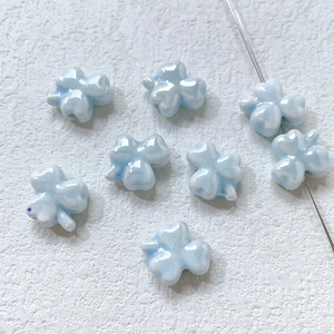 Macro detail of iridescent light blue ceramic clover beads for DIY jewelry making