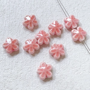 Flat lay of pink ceramic cherry blossom beads for DIY jewelry making and bracelets