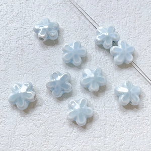 Detailed view of light blue ceramic clover beads with a pearlescent finish for DIY jewelry