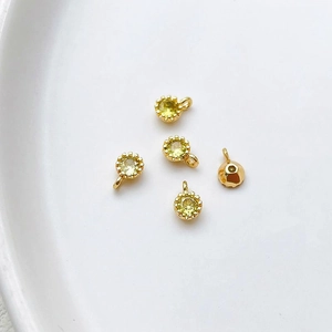Detalle de cinco colgantes redondos de circón amarillo con engaste dorado para joyas DIY