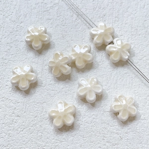 Close-up of small white ceramic flower beads with glossy glaze for DIY jewelry making