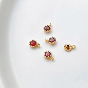 Detalle de colgantes bañados en oro 18k con circonitas rojas en engaste de garras