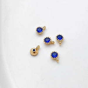 Detalle de cinco colgantes redondos de circón azul chapados en oro 18k para joyería DIY