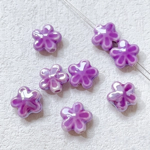 Macro detail of handmade purple ceramic clover beads with glossy finish and center hole
