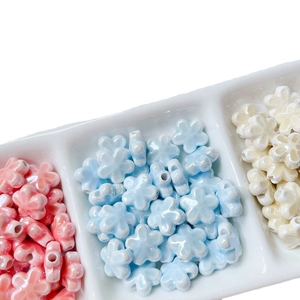 Lustrous ceramic four-leaf clover beads for DIY jewelry making in a white tray