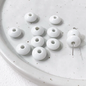Macro shot of white ceramic flat round beads for DIY jewelry making on a tray