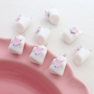 Macro shot of cute white ghost acrylic charms with pink heart gems for DIY jewelry making