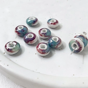 Macro shot of floral glazed ceramic donut beads and metal pins for DIY jewelry making