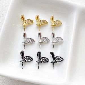 Dettaglio macro di ciondoli a foglia con zirconi placcati oro 14k in oro, argento e nero