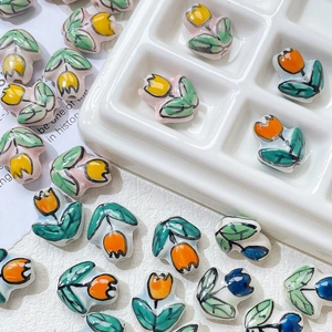 Close-up of hand-painted ceramic tulip beads in yellow, orange, and blue for DIY jewelry