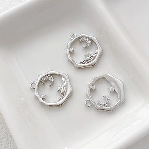 Macro shot of silver crescent moon and star charms with cubic zirconia inlay details