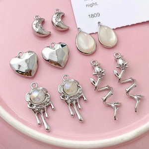 Silver alloy celestial and heart pendant charms set displayed on a pink ceramic tray