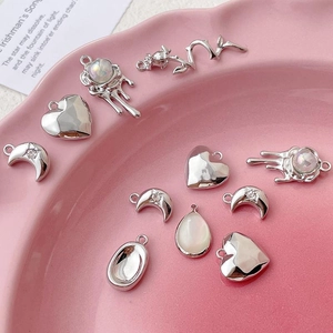 Silver liquid metal heart and celestial charms in a pink ceramic dish display