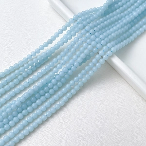 Gros plan de perles en pierre naturelle bleu clair pour bijoux DIY sur cuir blanc