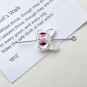Macro shot of silver cartoon monster cat face bead for DIY jewelry with pink cat eyes