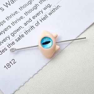 Detailed close-up of a funny monster cat jewelry charm with a blue eye inlay and silver pin