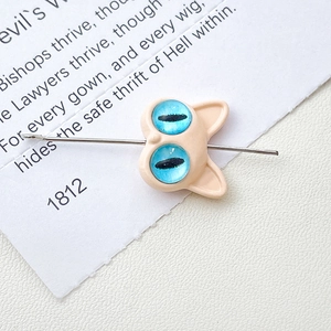 Macro shot of cartoon monster cat charm with striking blue eyes and silver pin detail