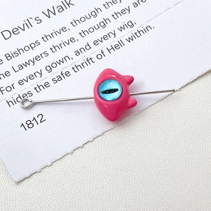 Macro shot of pink cat monster charm with blue evil eye bead and silver metal loop