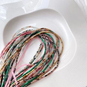 Bunte Naturstein-Zylinderperlen auf weißer Keramikschale für DIY-Schmuckdesign