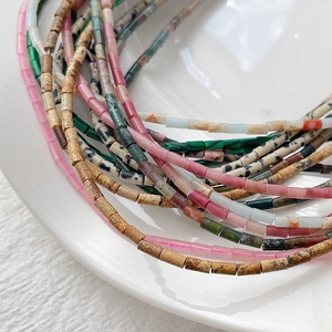 Makroaufnahme von 2x4mm bunten Naturstein-Röhrenperlen auf einer weißen Keramikplatte