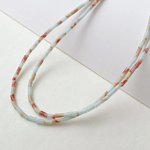 Makroansicht von 2x4mm Röhrenperlen mit natürlichen blau-orangen Marmortexturen