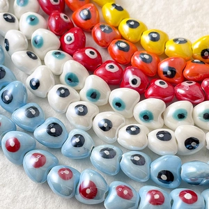 Detalle macro de cuentas de cerámica con forma de corazón y ojo turco para joyería artesanal