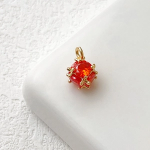 Dettaglio macro del ciondolo a cubo placcato oro con zircone rosso arancio sfaccettato