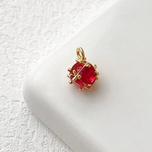 Dettaglio di un ciondolo in zircone rosso sfaccettato con montatura a gabbia placcata oro 14k