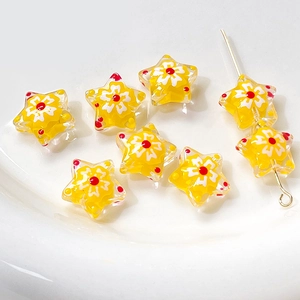 Macro view of yellow star glass beads with floral hand-painted details for DIY jewelry