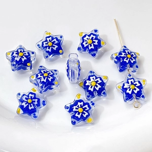 Macro view of blue star-shaped lampwork glass beads with white floral patterns