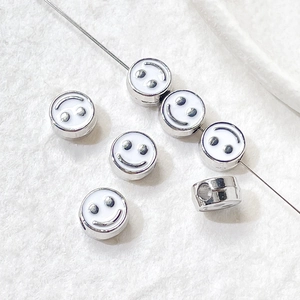 Detailed view of smiley face enamel beads on a thin wire for DIY jewelry making