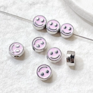 Macro view of silver alloy smiley face beads with pink enamel for DIY jewelry making