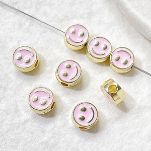 Macro shot of pink enamel smiley face bead with gold-plated metal finish for DIY jewelry